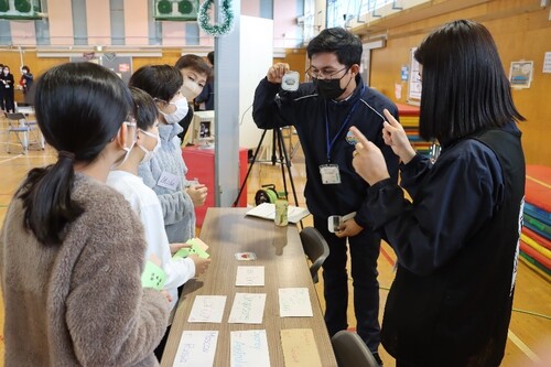 世界の都市名が記載されたカードと天気が記載されたカードを選ぶ児童たちの写真